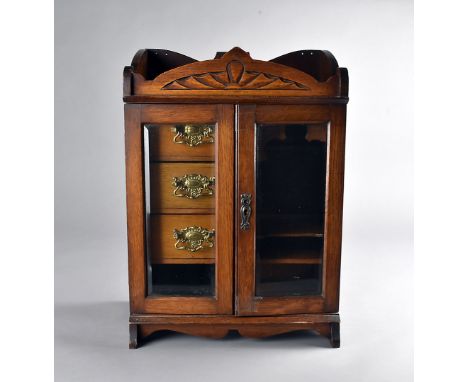 An Edwardian oak smokers bow cabinet with glazed panel doors, to fitted interior with three drawers and pipe rest, 47 cm x 33