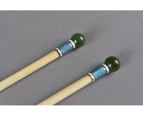 A cased pair of Edwardian knitting needles, the ivory needles of turned cylindrical form having enamel terminals surmounted b