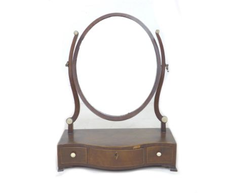 A 19th century mahogany toilet mirror, with oval shaped plate, below three serpentine fronted trinket drawers with turned bon
