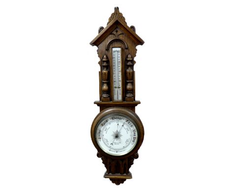 An oak cased aneroid barometer and thermometer, by Harris & Son, Spalding, circa 1940, the case carved with foliate decoratio