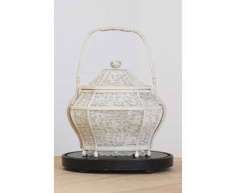 An ivory cricket cage,19th century, in the form of a basket with tall loop handles over a detachable cover, worked and pierce