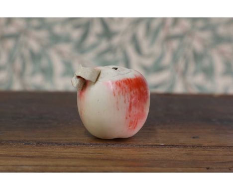 A carved and stained ivory okimono,Meiji period (1868-1912), Japanese, in the form of an apple with a partially-peeled skin,7