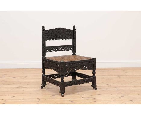 A carved ebony low chair,probably early 19th century, Indian, Coromandel Coast, the carved bar back decorated with mythical c