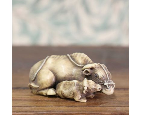 An ivory netsuke,Meiji period (1868-1912), Japanese, of a recumbent buffalo with a calf to its side, signed 'Masanao' to the 