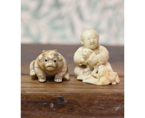 An ivory netsuke,Meiji period (1868-1912), Japanese, carved with a boy playing with two puppies, signed 'Shounsai' to the bac