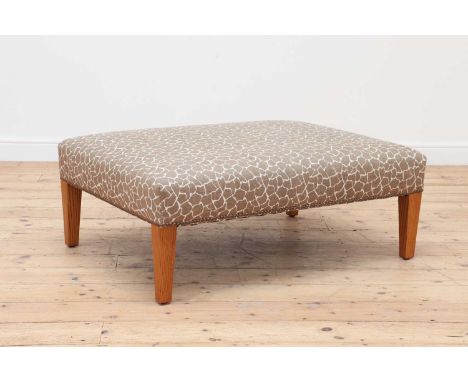 An upholstered footstool by George Smith,with oatmeal and cream upholstery, raised on square tapering oak legs, with maker's 
