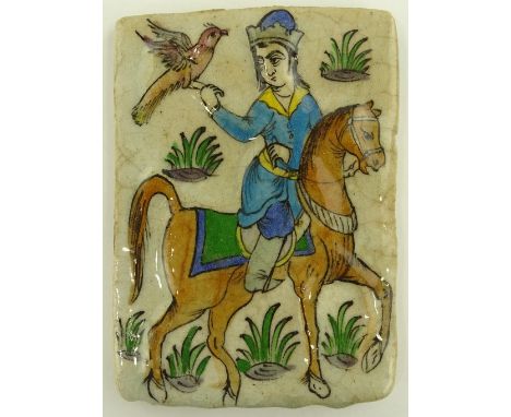 An Islamic relief decorated and painted pottery tile depicting a huntsman and hawk, height 18.5cm.