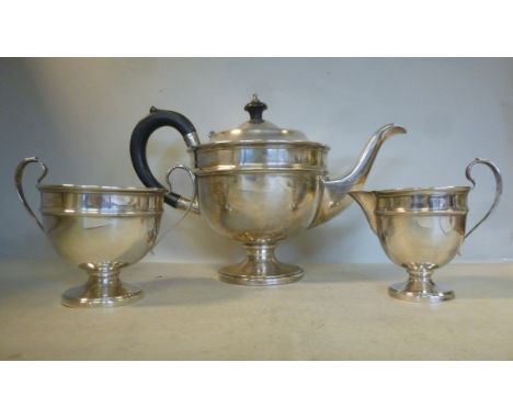 A three piece silver tea set of pedestal bowl design  comprising a teapot with an ebonised, high loop handle and knop to the 