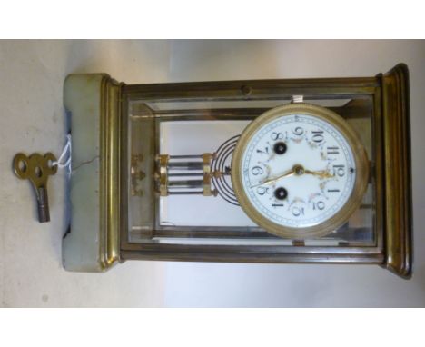 A 1920s four glass and brass framed mantel clock, on a green onyx bracket plinth; the gong strike movement with a compensatin