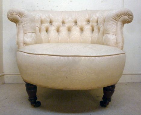 A late Victorian tub chair, having a horseshoe shaped back, part button upholstered in a cream coloured floral fabric, raised