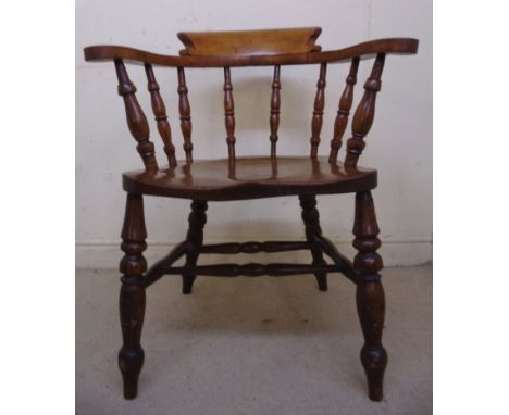 A late Victorian beech and elm framed desk chair, having a curved crest, level arms and a spindled back, the moulded solid se