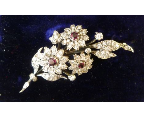 A gold coloured metal ruby and diamond set floral spray brooch