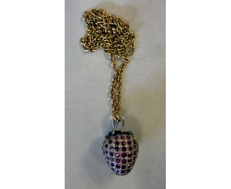 A white coloured metal and ruby set strawberry pendant, on a yellow metal neckchain