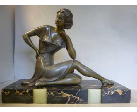 An Art Deco cast and patinated spelter figure, a fashionable young woman, seated on a black and light green onyx box plinth  