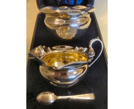 An Edwardian silver cream jug of squat, bulbous form with a high loop handle and a flared wavy rim, a matching sugar basin an