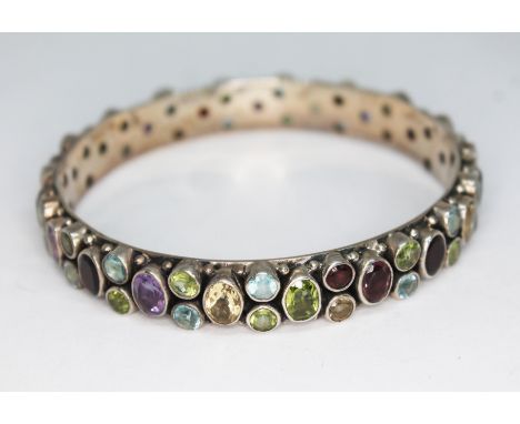 A white metal multi-gem stone bangle, diam. 6cm. 