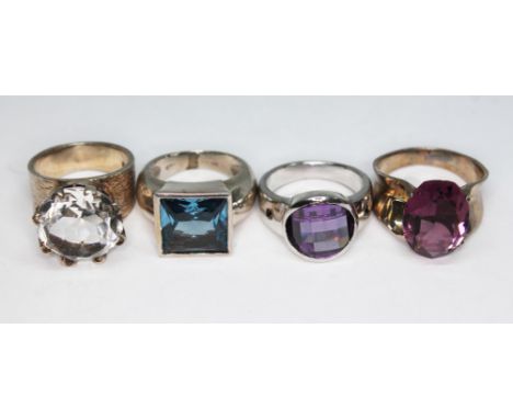 A group of four contemporary crafts rings comprising one hallmarked silver set with a round mixed cut rock crystal quartz, a 