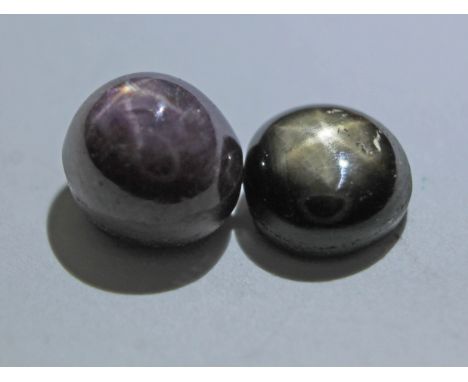 Two corundum variety cabochons displaying six rayed star asterism comprising a star ruby weighing 4.95 carats and a brownish 