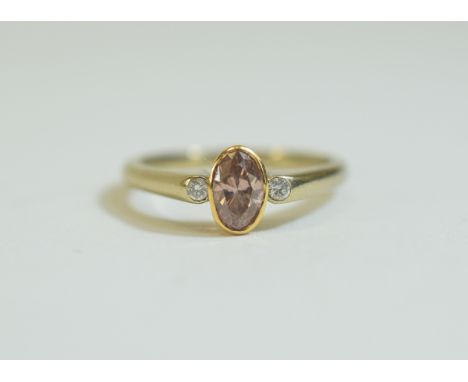 18ct Gold 3 Stone Ring Set with An Oval Brilliant Cut Natural Pink Diamond, Flanked by Two Round Brilliant Cut Diamonds. The 