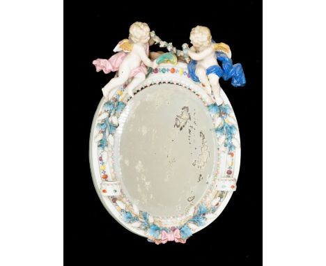 A 19th Century porcelain oval girandole mirror, the body surmounted by a pair of Putti holding a garland of flowers, the fram
