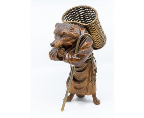 An Asian carved hardwood figure of a fox, wearing robes, carrying a metal basket on his back and supported by a stick, glass 