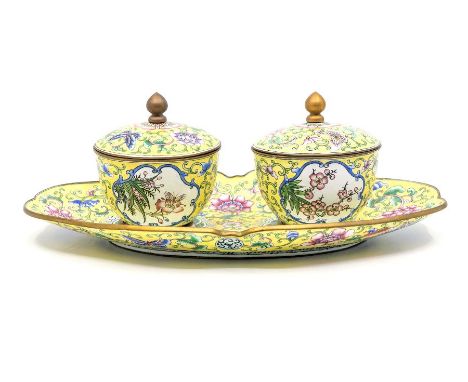 A painted enamel condiment set, late Qing Dynasty, comprising two jars and covers and a shaped stand, all painted with butter