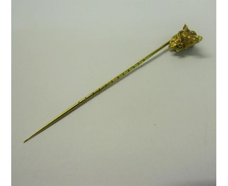 An Edwardian gold stick pin with a dog's head terminal, having ruby eyes, collar with bell.  9.5cms l. 3.9g. 