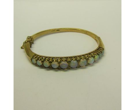 A gold bangle set with eleven graduated opals - 23g overall. 