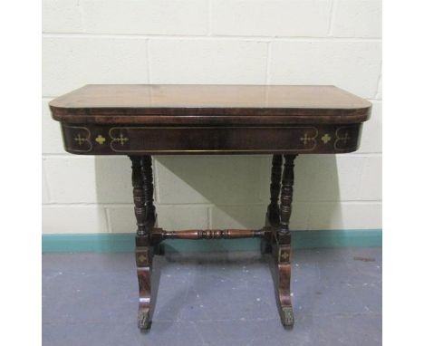 A late Georgian figured mahogany fold over card table the table top with brass rail inlay cross banded in rosewood and with g