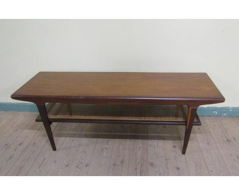 A 1970s teak low table of rectangular form with a caned under tier shelf, supported on straight tapering legs.  136cms w x 47