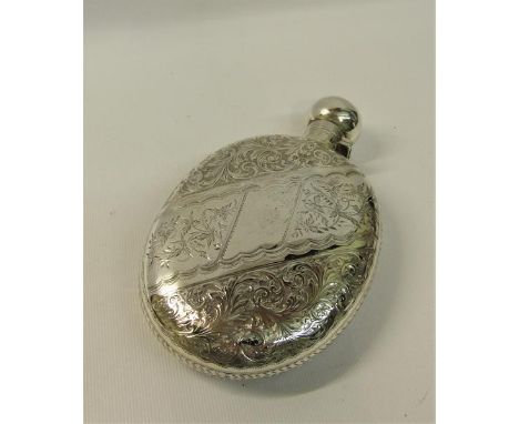 An Edwardian silver pocket flask of oval form incised with bands of scrollwork and flowers with a hinged dome screw top.  Mak