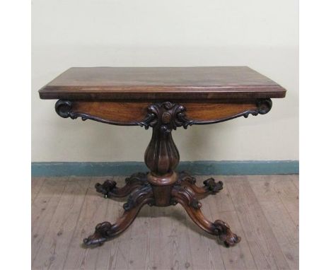 A William IV rosewood fold over card table with scroll moulded frieze supported on a lobed baluster column, raised on a circu