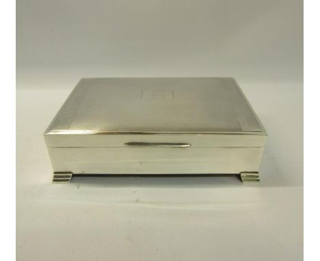 A silver cigarette box of rectangular form with engine turned panels to the hinged cover, fitted two compartments and support