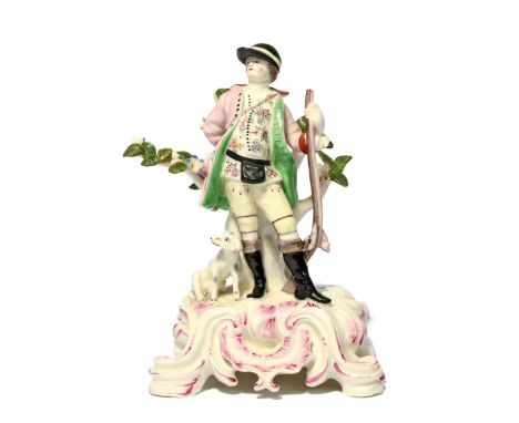 A Bow figure of a huntsman c.1760-65, wearing a peaked hat and holding a barrel of a long gun, his dog seated by his right fo