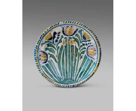 A delftware tulip charger of small size  c.1690, probably London, painted with three large tulips flanking other flowers abov