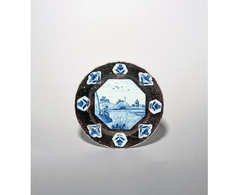 A Lambeth delftware plate  c.1720, painted in blue with an octagonal panel of a European figure fishing from a riverbank with