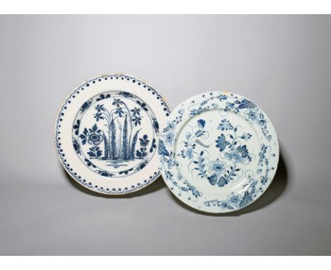 Two large delftware chargers  c.1750-70, one probably Liverpool and painted in a dark blue with flowers and feathery leaves w