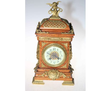An early 20th Century oak and brass mounted mantel clock having cherub finial and enamel dial, 40cm high.