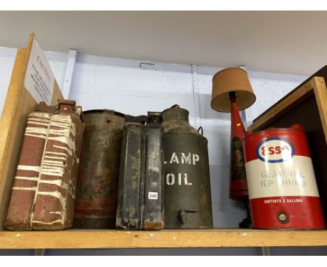 Shelf containing two Jerry cans, three oil drums and a homemade lamp