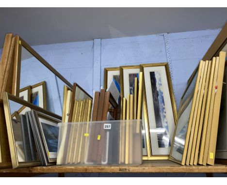Shelf of printed artwork including seascapes, and mirrors.