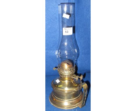 Brass double burner oil lamp with brass reservoir and base, having loop handle and glass chimney.