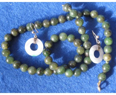Graduated string of spinache jade beads, together with a paid of silver mounted jade earrings.