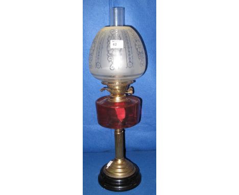 Early 20th Century brass double burner oil lamp with cranberry glass reservoir on a brass pedestal with ceramic base.  Etched