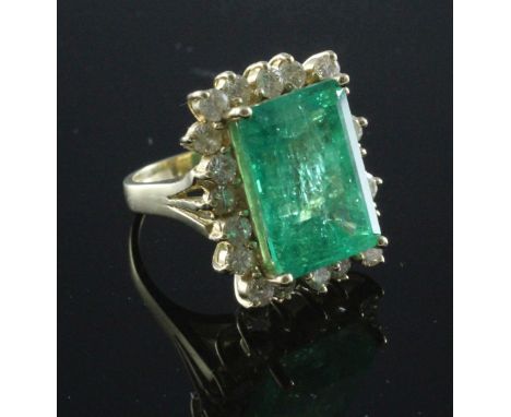 A large 14ct gold emerald and diamond rectangular cluster ring, with central 14.57ct emerald within a border of brilliants, w