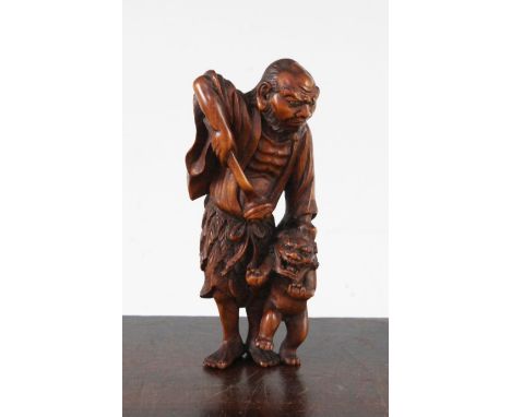 A Japanese boxwood okimono netsuke of a Sennin and a shi-shi, early 20th century, the standing figure of the Sennin holding a