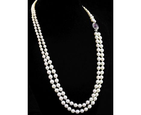 A double strand graduated cultured pearl necklace with a white metal, purple tourmaline and diamond set circular clasp, 16.5i