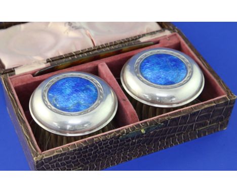 A cased pair of George V Arts & Crafts silver and blue enamel mounted clothes brushes by W.H. Haseler Ltd,, of circular form,