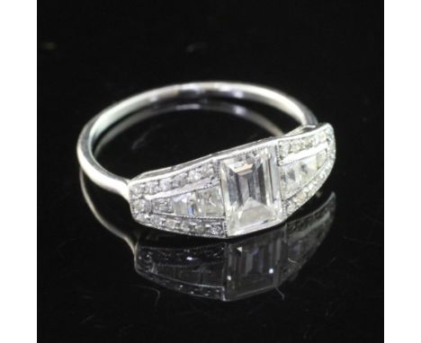 A 1930'/1940's white gold and diamond elliptical shaped ring, with central emerald cut diamond and graduated trapeze cut diam