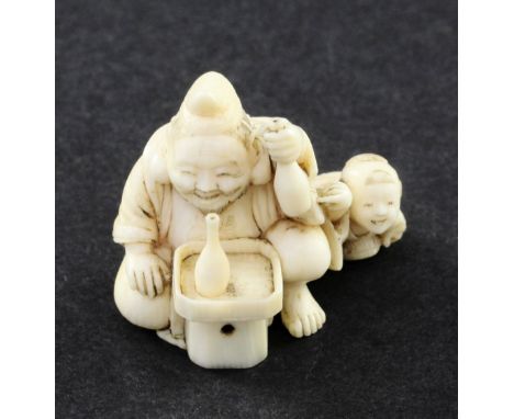 A Japanese ivory netsuke of Ebisu and a boy, Meiji period, seated at a table with two bottles of sake, engraved two character