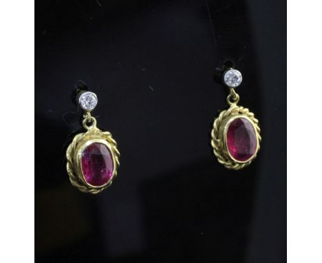 A pair of 18ct gold, ruby and diamond set drop earrings, of oval form, with spiral border.